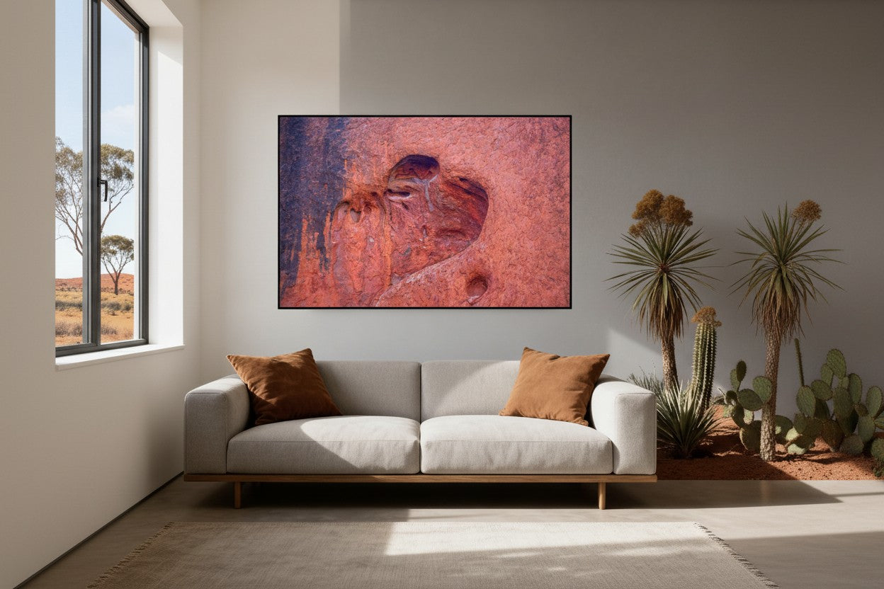 Heart of Uluṟu fine art print in a thin black frame on a grey wall above a cream sofa with terracotta cushions in a bright minimalist Australian living room with outback views — unframed