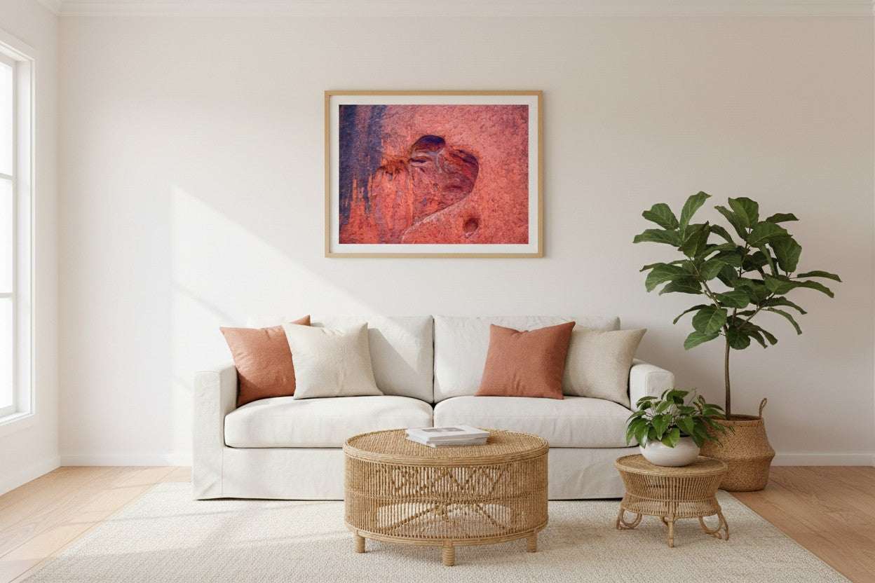 Heart of Uluṟu fine art print in a thin timber frame above a white linen sofa in a bright Australian living room with terracotta and rattan accents — unframed wall art