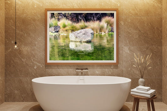 Kōhatu fine art print of a New Zealand river boulder displayed above a freestanding bathtub in a luxury spa bathroom — unframed wall art