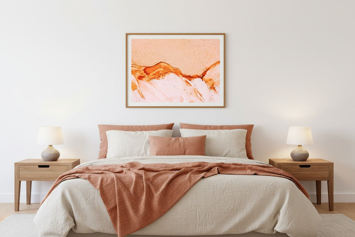 K'gari Sand fine art print in a thin timber frame above a bed in a warm coastal bedroom with cream and terracotta linen — unframed Fraser Island wall art