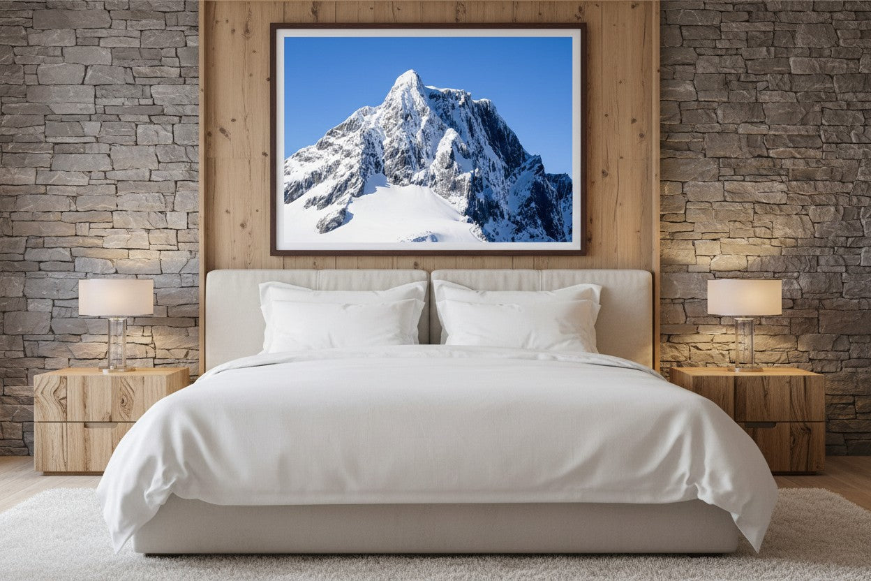 The Limit fine art print above a bed in a luxury alpine bedroom with timber and stone — unframed mountain photography